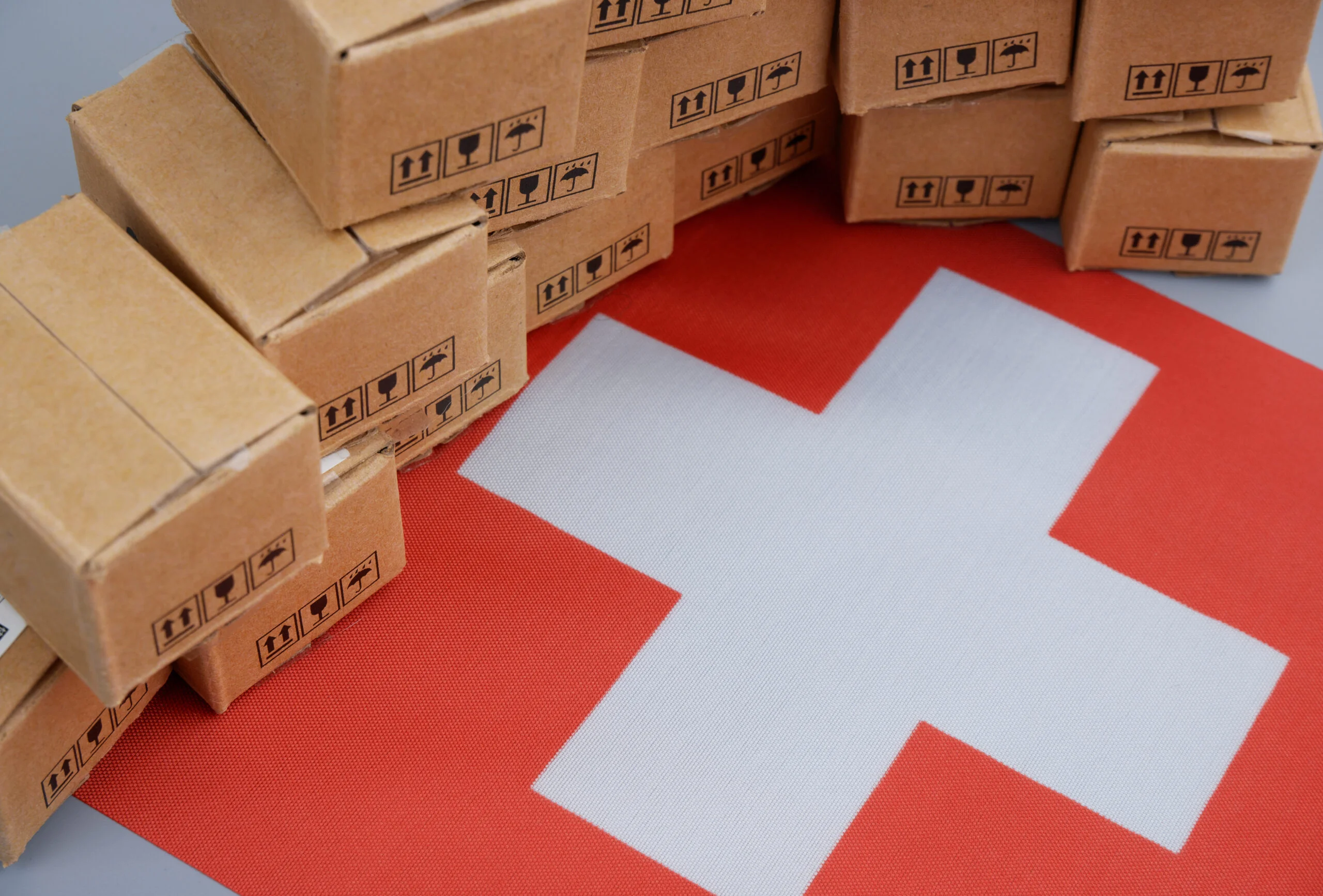 Colis en carton disposés autour d’un drapeau suisse.