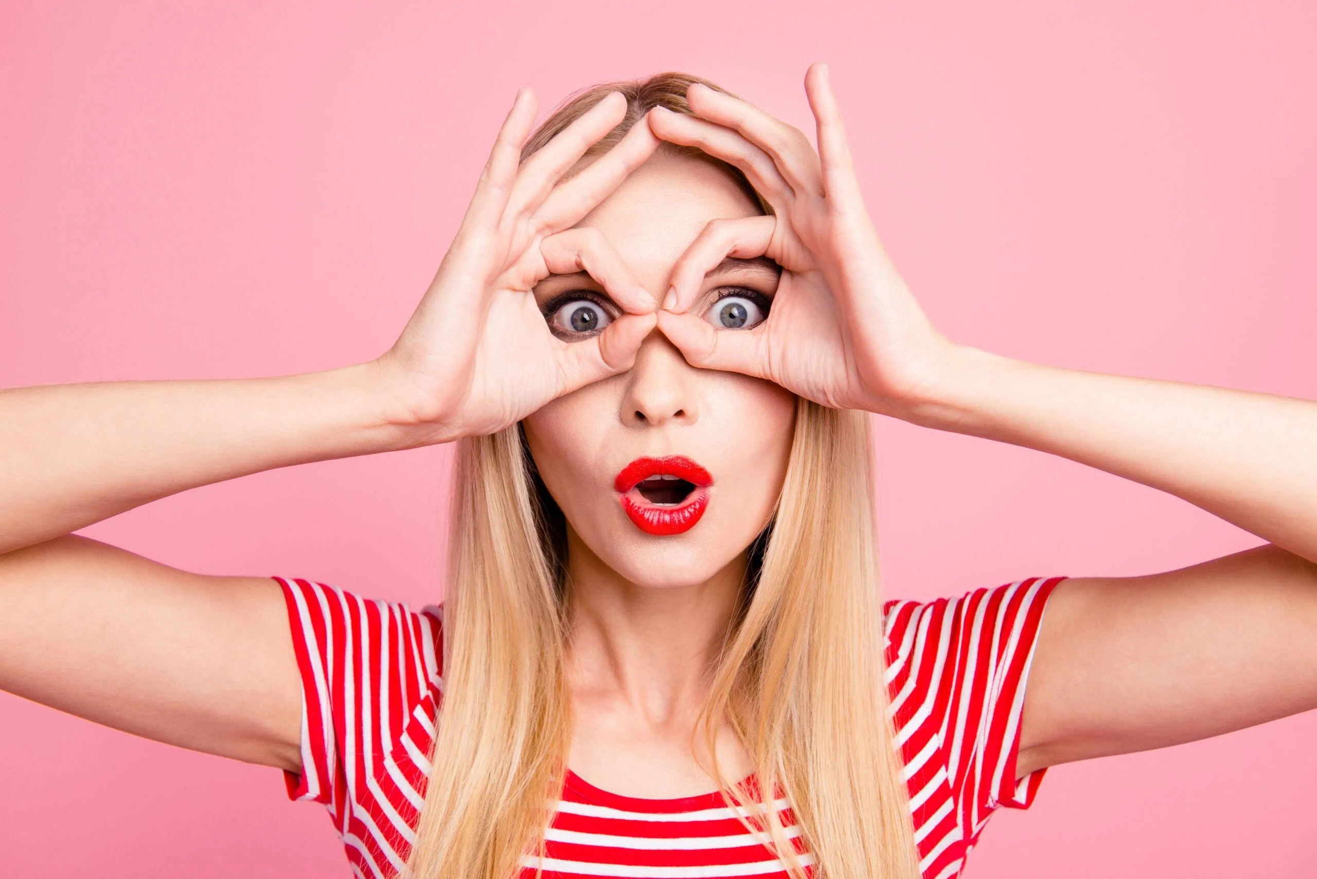 Femme faisant des lunettes avec ses mains devant ses yeux.