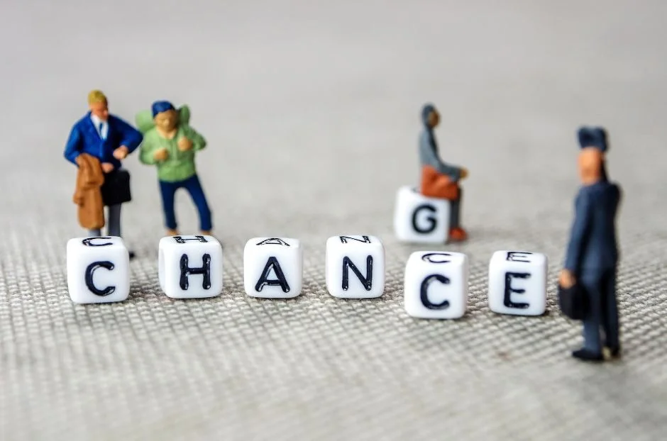 Des personnages miniatures se tiennent autour de dés lettrés épelant “CHANGE”, avec un dé en arrière-plan épelant “CHANCE”, sur une surface texturée, symbolisant l’accompagnement et la résistance des employés lors de l’adoption de nouveaux outils digitaux.