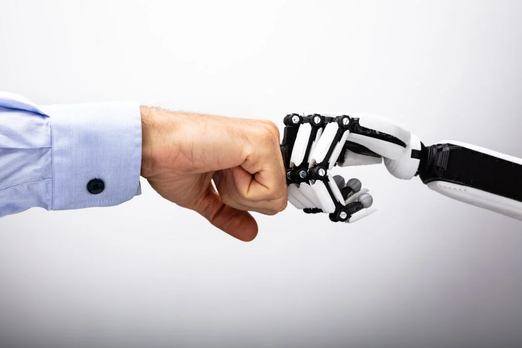 Poing humain au contact d’une main robotique.