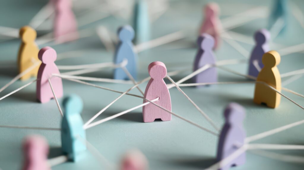 Figures humaines en bois coloré reliées par une ficelle blanche, illustrant un concept de réseau ou de connexion sociale sur une surface bleu clair - une métaphore visuelle efficace pour une forte culture d'entreprise et l'intégration de l'ERP au sein des organisations.