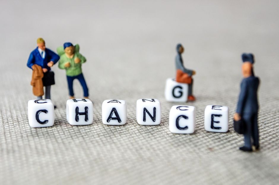 Des personnages miniatures se tiennent autour de dés lettrés épelant "CHANGE", avec un dé en arrière-plan épelant "CHANCE", sur une surface texturée, symbolisant l'accompagnement et la résistance des employés lors de l'adoption de nouveaux outils digitaux.