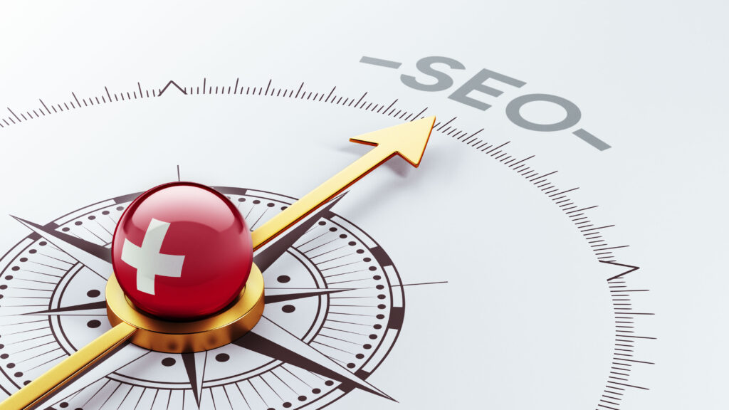 A compass with a golden arrow pointing to the word “SEO” and a red button bearing a white cross, symbolising the direction or the emphasis placed on SEO analysis and the latest 2025 SEO trends.