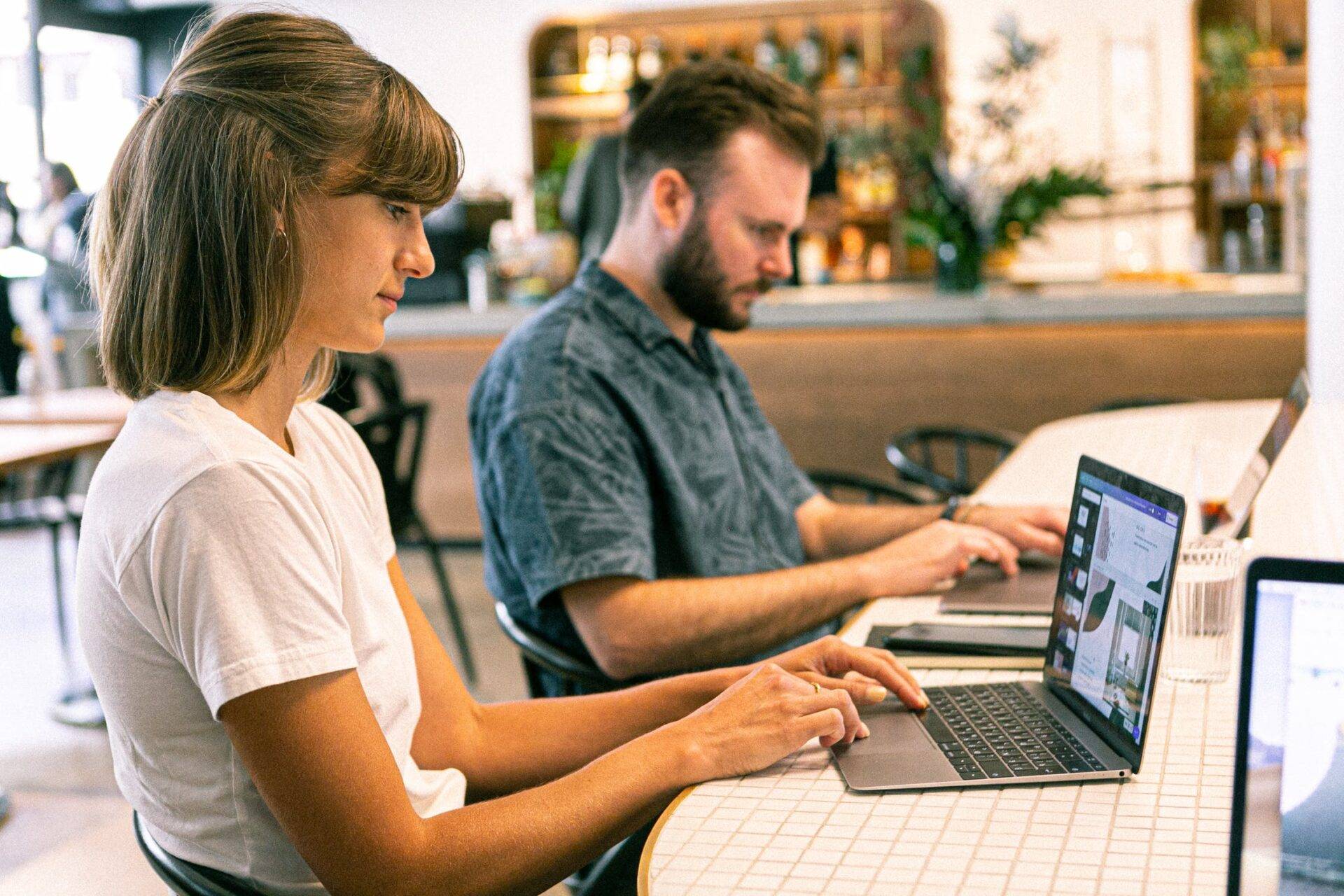 Deux personnes travaillant sur des ordinateurs portables dans un café.