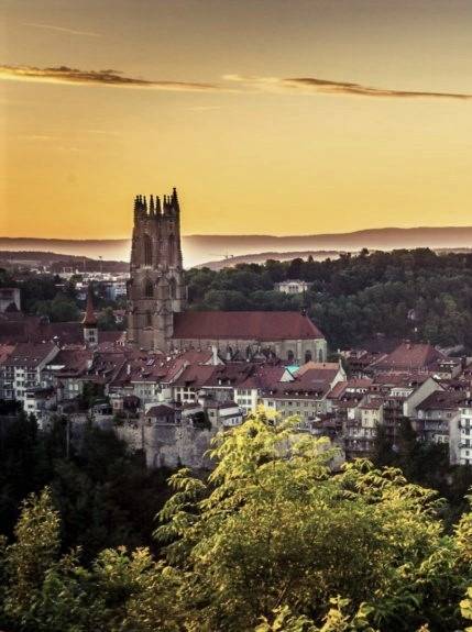 Une ville au coucher du soleil avec une église en arrière-plan à Fribourg.