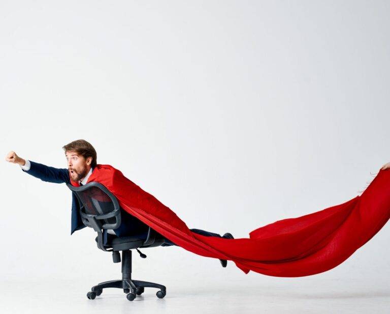 Un homme d’affaires portant une cape rouge est assis sur une chaise de bureau dans l’agence numérique suisse Smart Impact.
