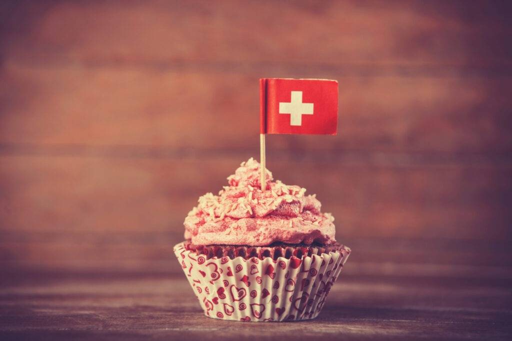 Un cupcake avec un drapeau suisse se dresse élégamment.