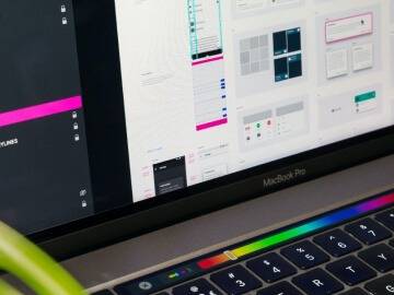 Gros plan d'un MacBook Pro affichant un logiciel de conception graphique à l'écran.