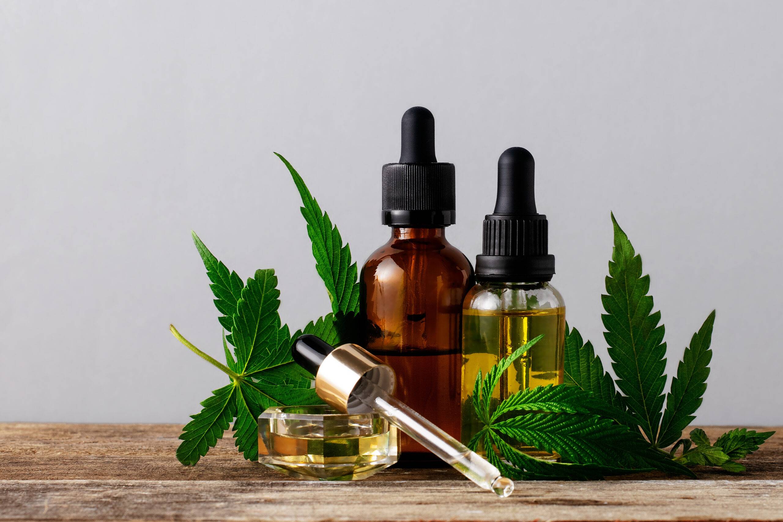 CBD oil bottles with droppers and cannabis leaves displayed.
